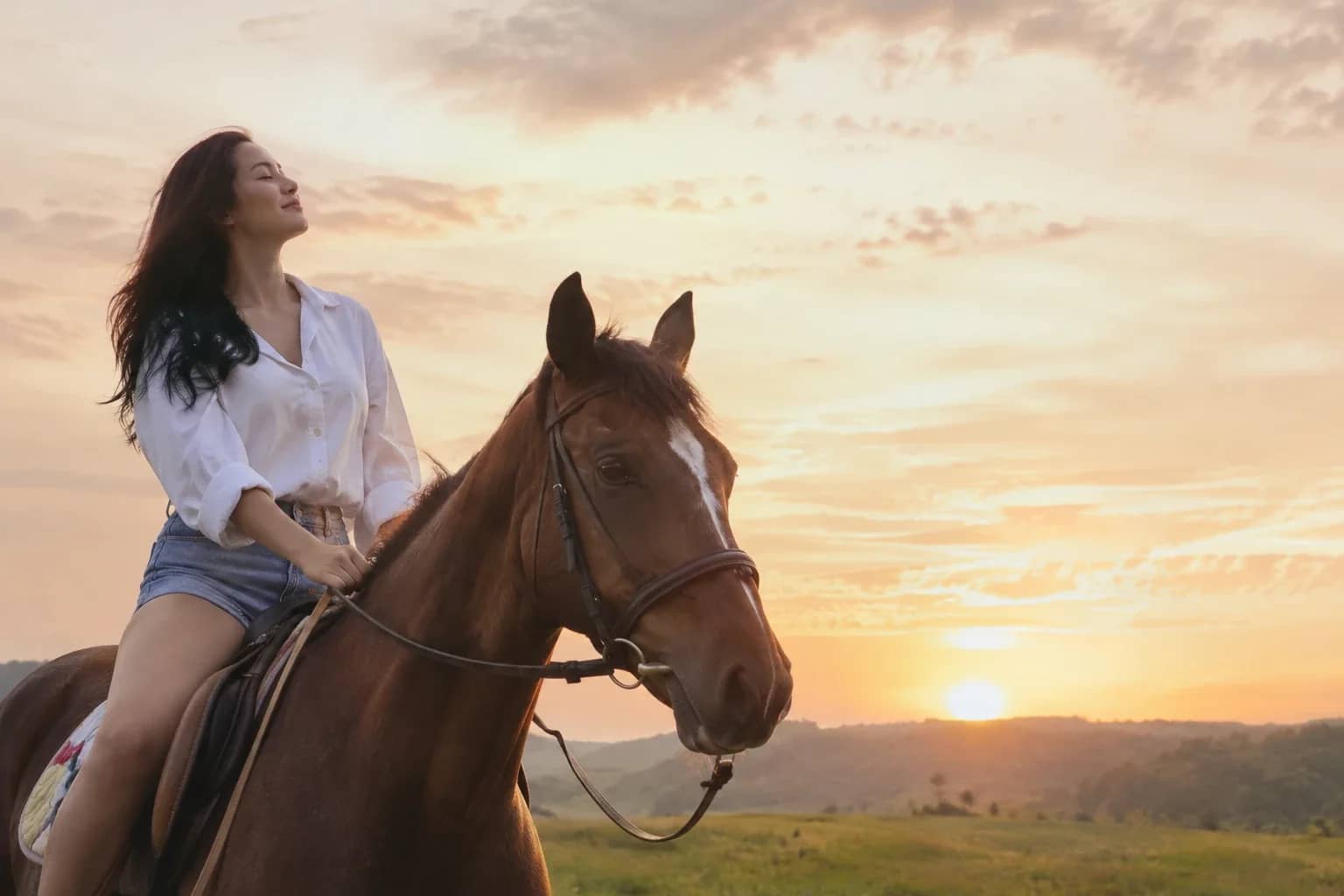 A rider at ease on her horse at sunset, eyes closed, face to the sky