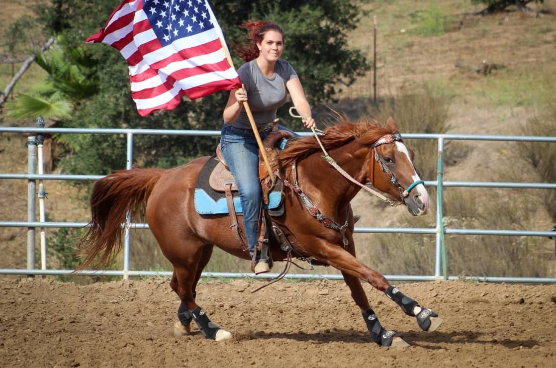Rider carrying the flag at a gallop across the arena