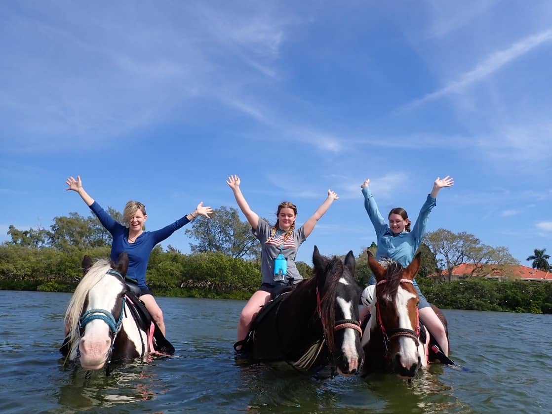 Three riders in open water, arms thrown up